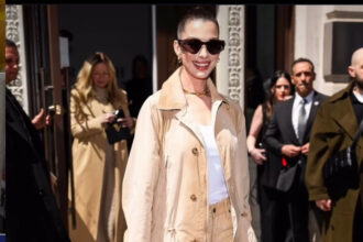 Anne Hathaway Attended the Ralph Lauren FW ’25 Show in a Khaki Trench Coat and Sequined Jeans